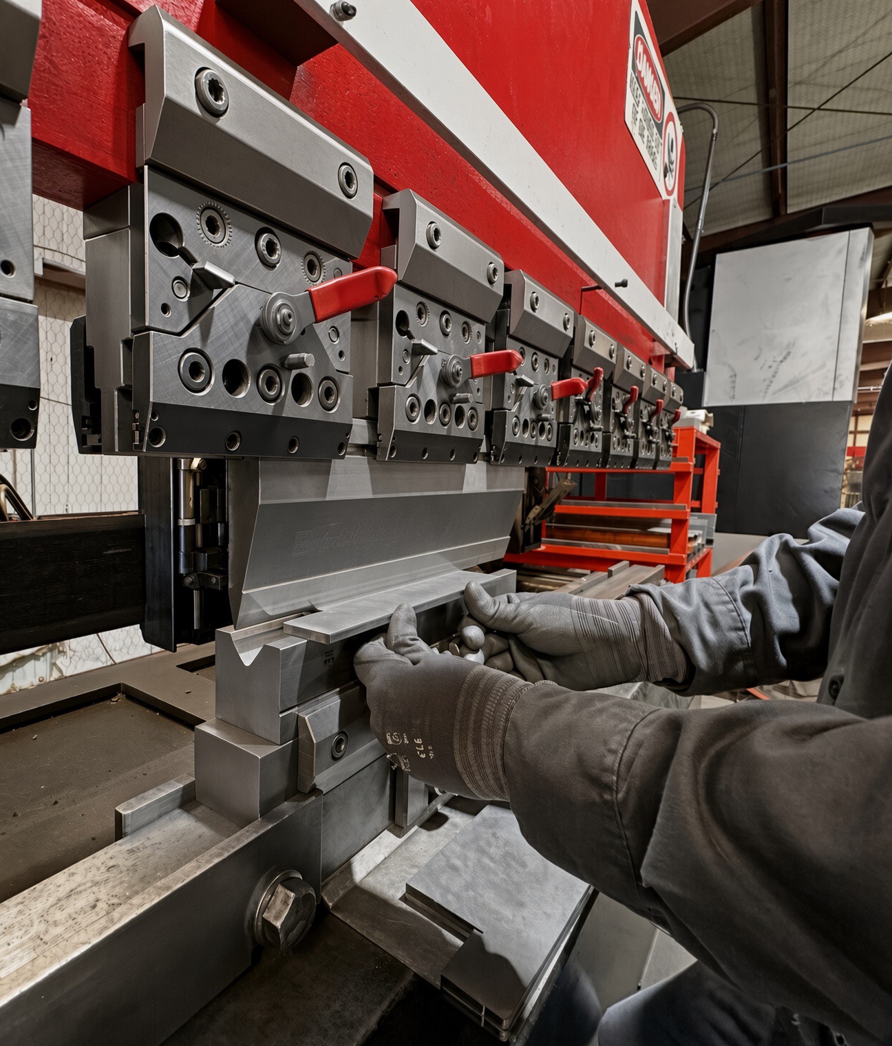 Gloved hands setting a blank against the press brake back gauge
